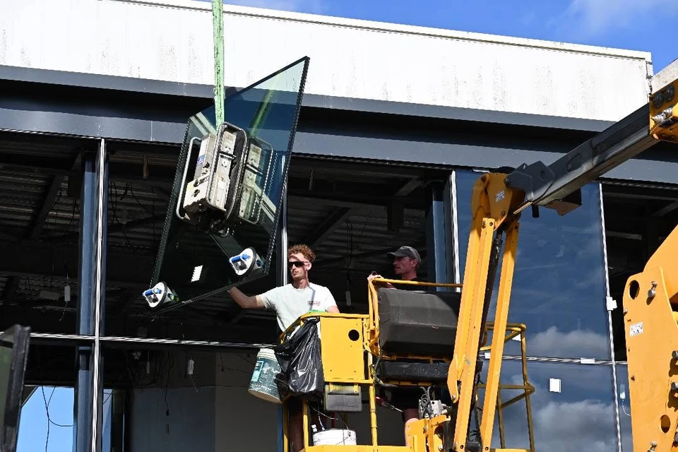 Travailleur en uniforme à l'aide d'une bande de mesure lors de l'installation de stores de fenêtre horizontaux à l'intérieur