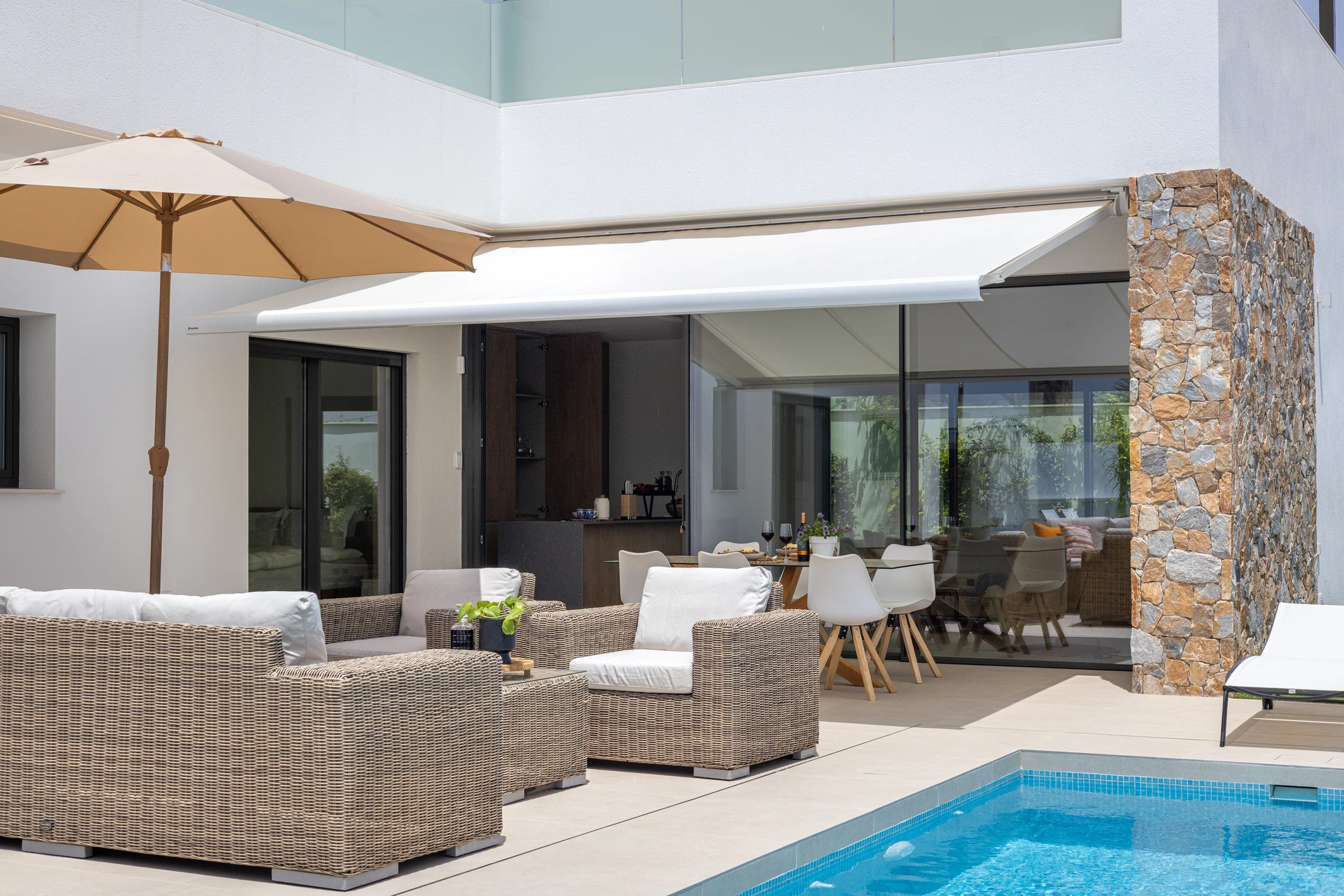 Terrasse extérieure avec store banne déployé offrant protection solaire, structure métallique apparente et végétation visible en arrière-plan